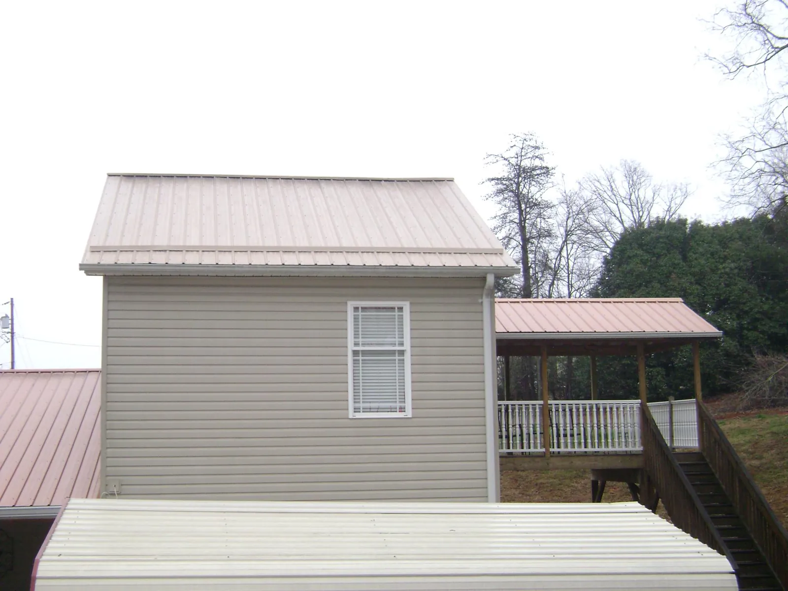 Tan metal roofs on a two story addition and attached porch, from a Roof Replacement job in Georgetown